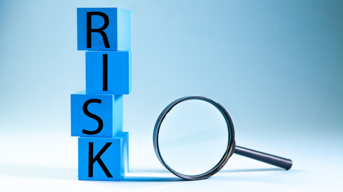Trading Top Tip: Cut Losses Early — Blue blocks spelling risk next to a magnifying glass