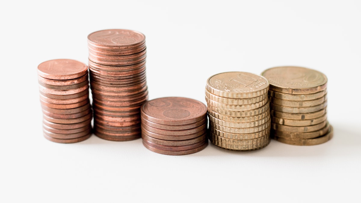 The Power of Compounding Growth — stacked round gold-colored coins on white surface