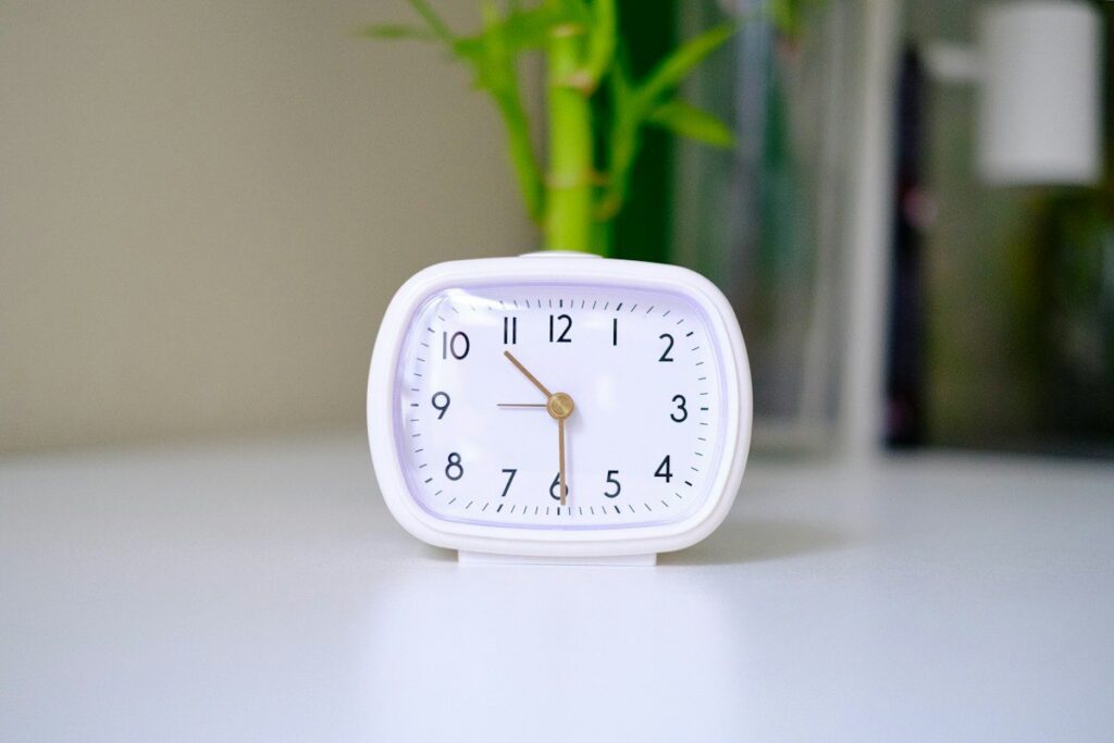 White alarm clock on a desk, marking the end of a fixed trading session
