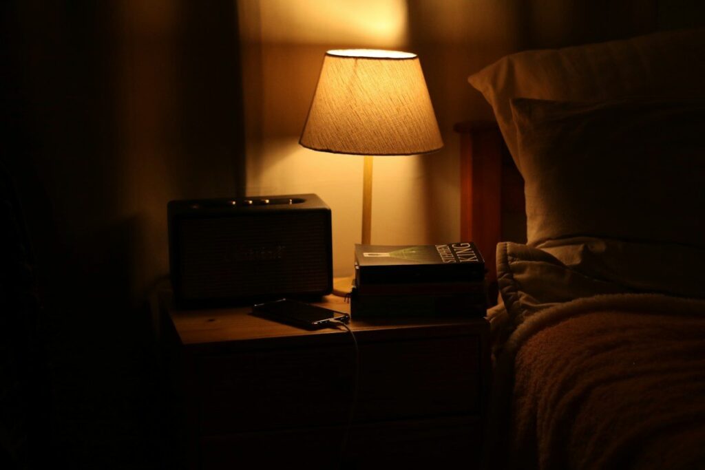 Lamp lit on a bedside table at night, a reminder that rolling spread bets pay overnight funding