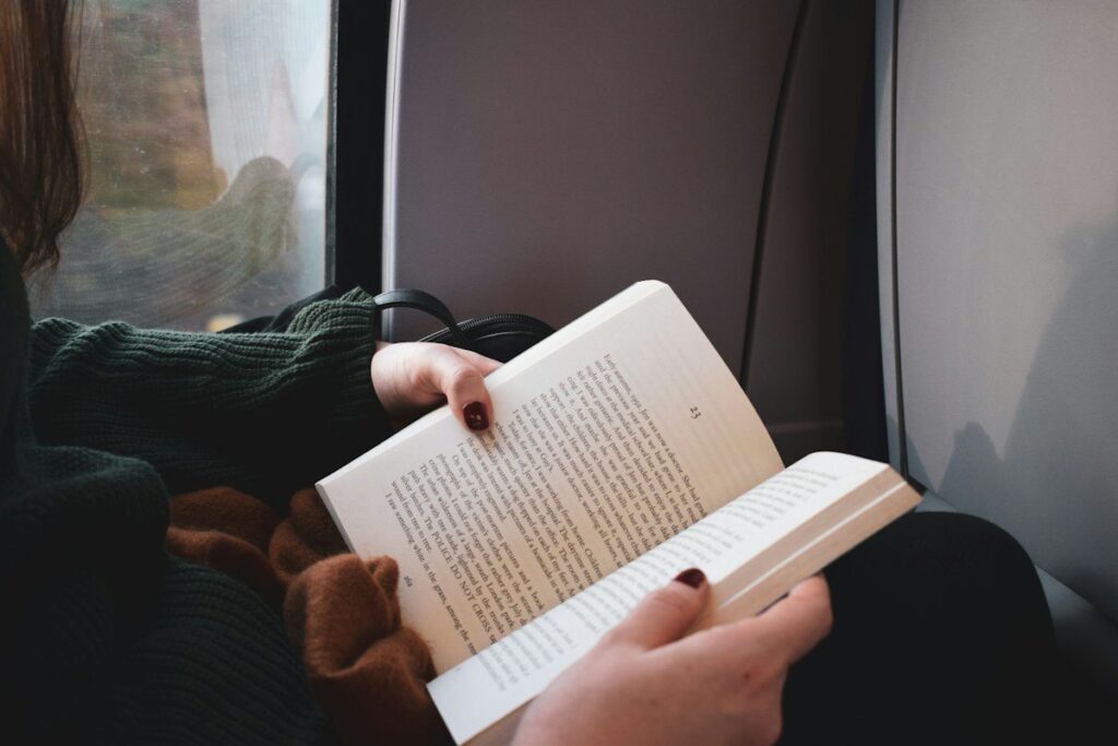 Beginner reading a book on a train commute while learning the foundations of trading