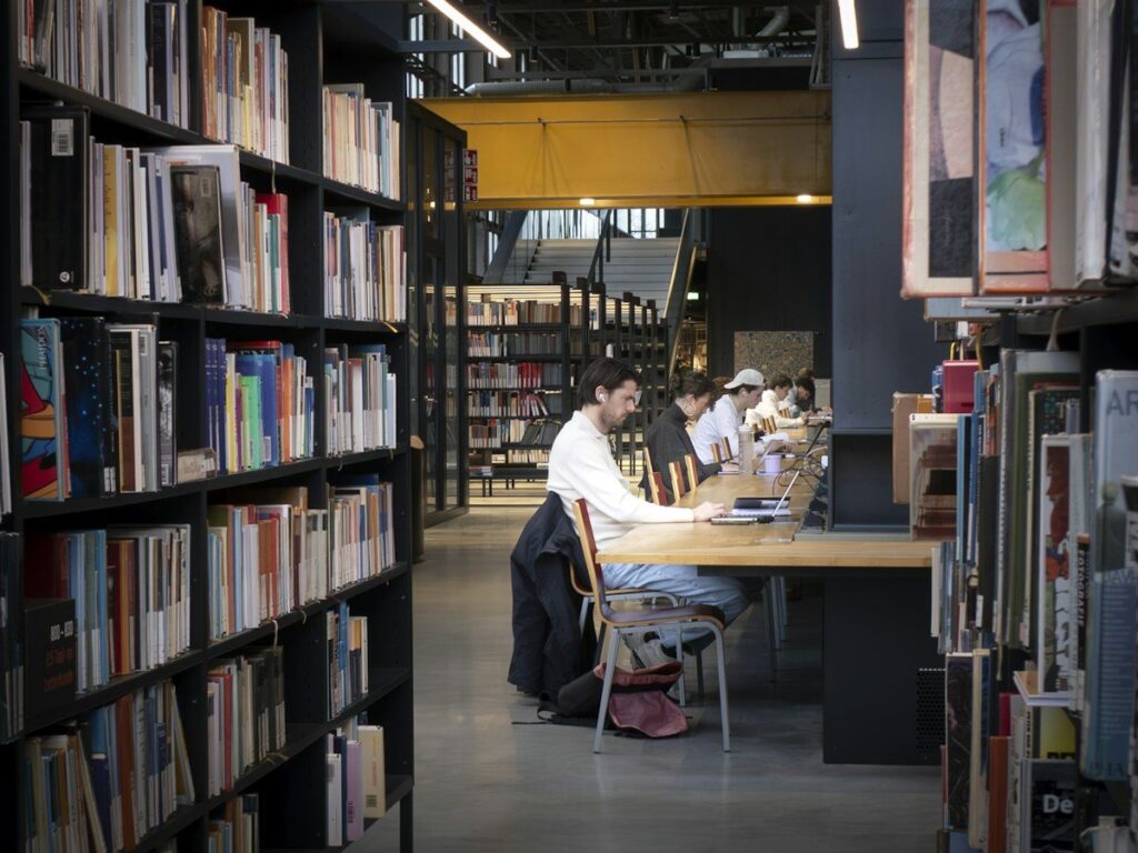 Student reading notes at a library table, learning to read price before adding indicators