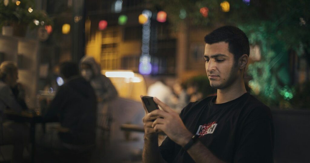 Person checking a trading app on a smartphone in a cafe, reviewing a small account balance