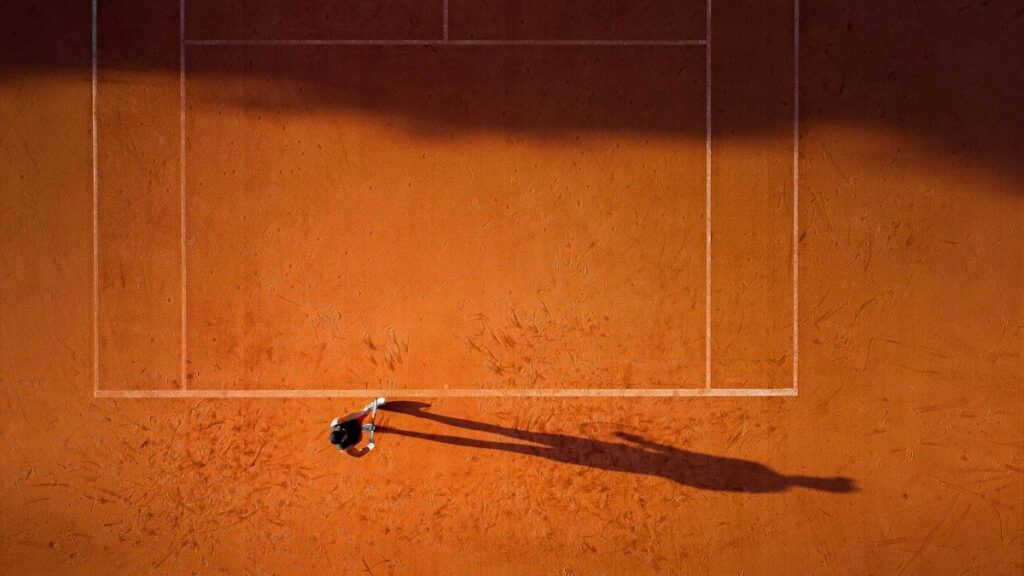 Tennis player on a clay court seen from above, like price returning to touch a trendline