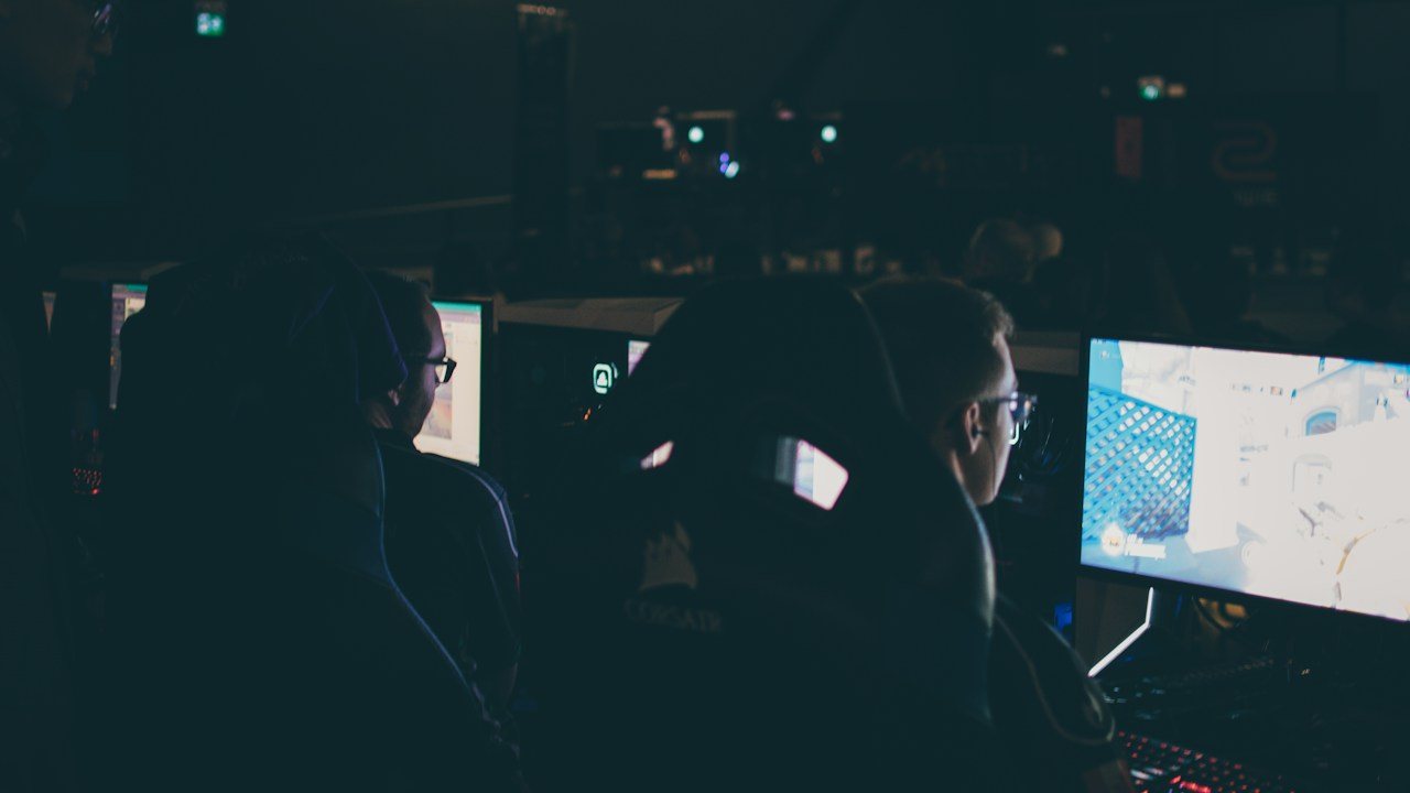 Two people at monitors in a dark room