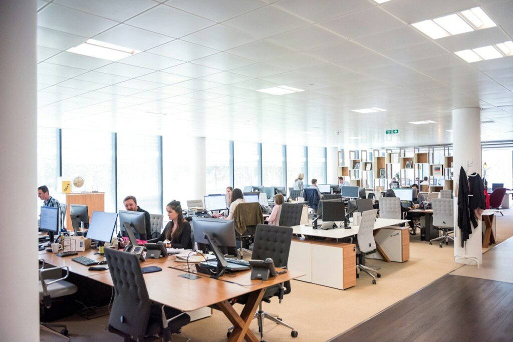Busy open-plan office with rows of desks and screens