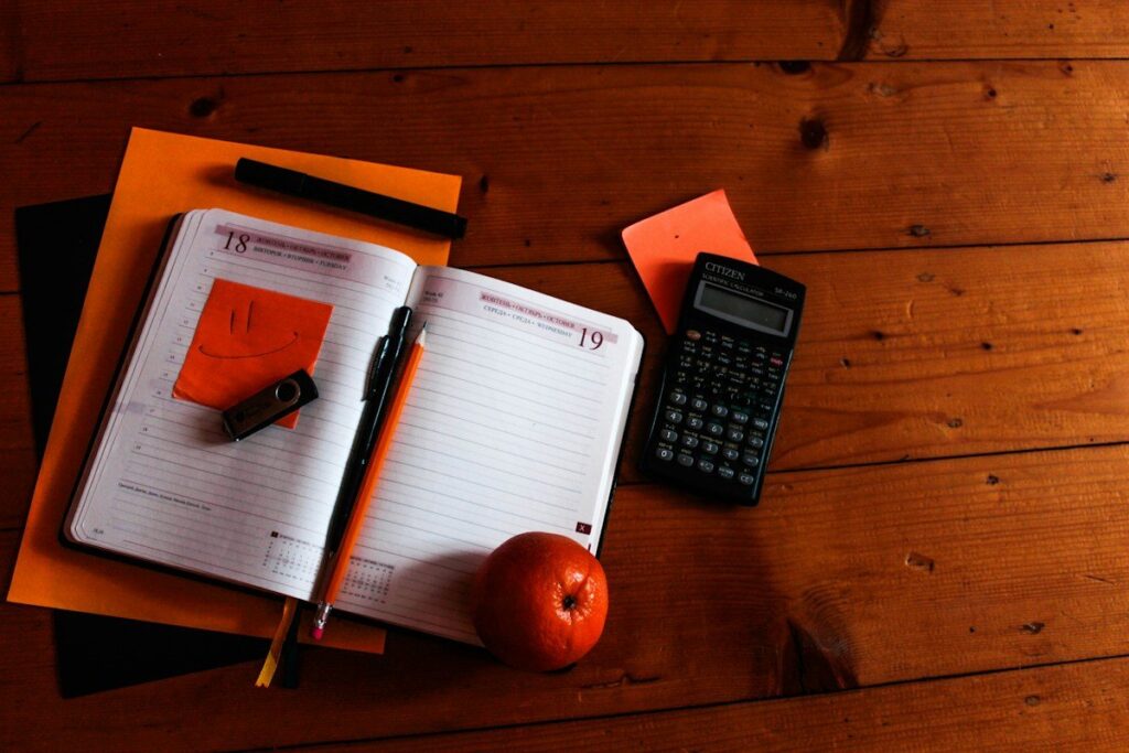 Calculator and pencil on a notebook, used to add up how a revenge trading sequence escalates risk