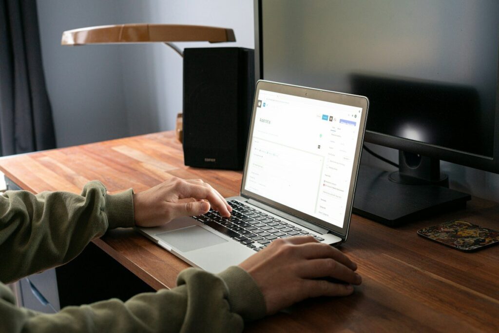 Person typing on a laptop at a wooden desk