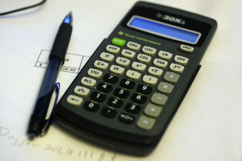 Calculator resting on a notepad while working out the position sizing rules of a trading system