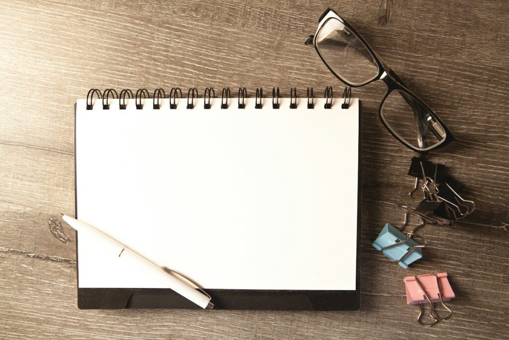 Notepad and glasses on a desk for planning an early versus a confirmed entry in a new trend