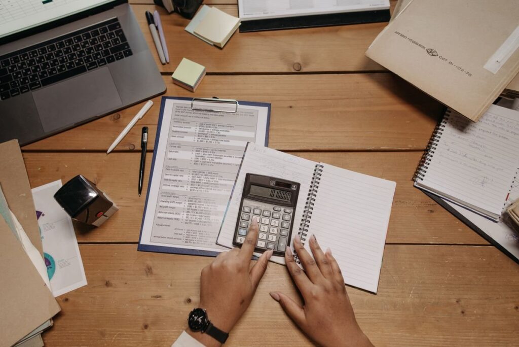 Calculator and notepad on a table, working out stake size for two forex pairs with different ranges
