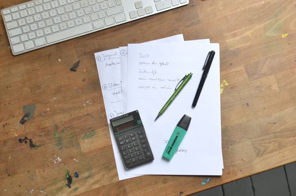 Calculator and pen on squared paper, used to work out risk per trade before a first trade