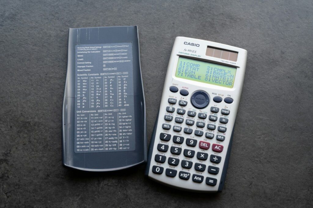 Calculator beside a printed sheet, used to compare the yearly cost of two trading courses
