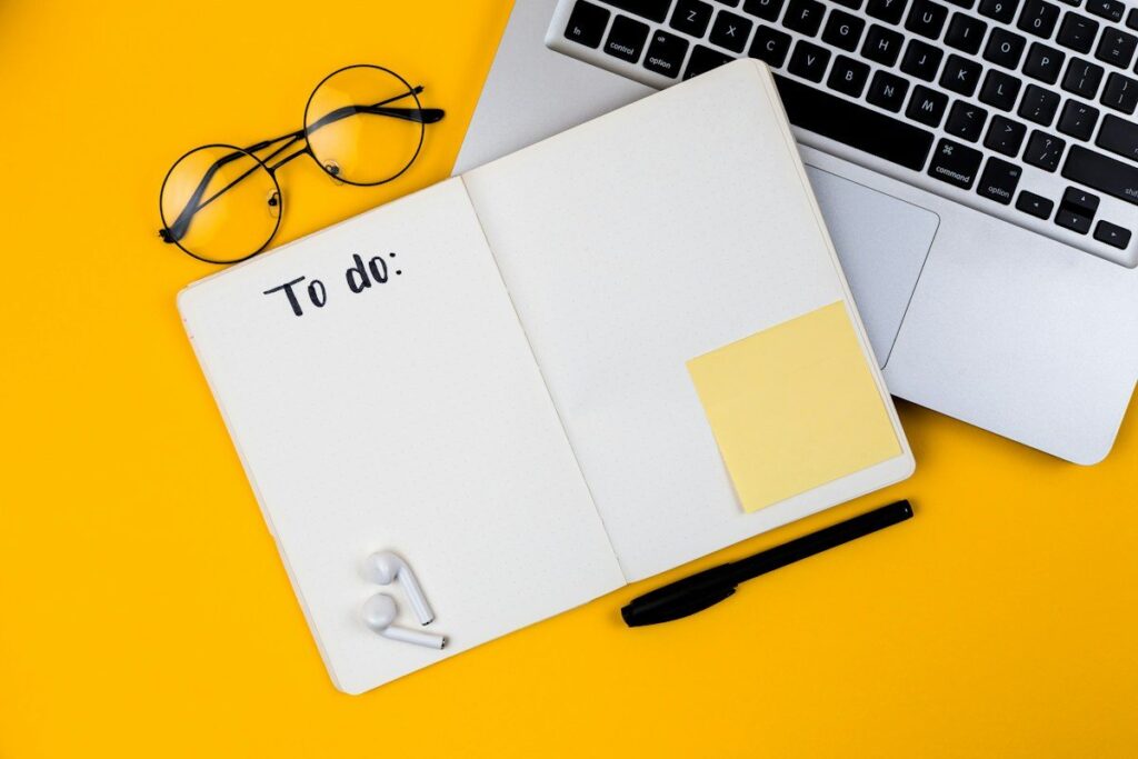 Notebook with sticky notes beside a laptop while setting the risk rules in a trading plan