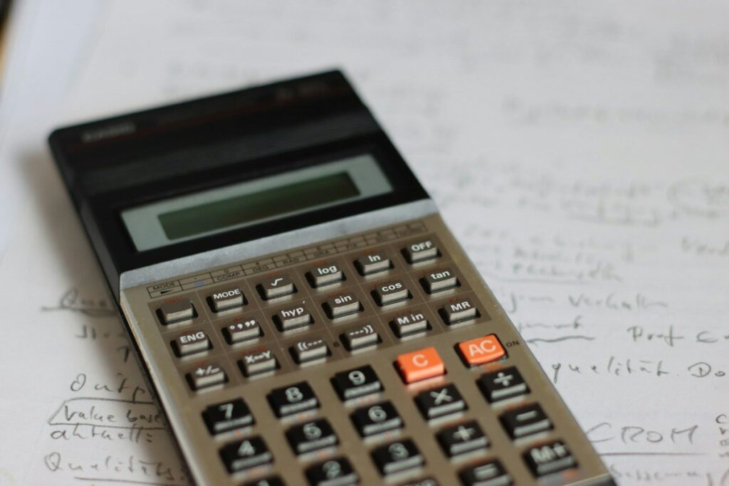 Calculator and pencil on a notepad used to check a pin bar trade's reward against its risk