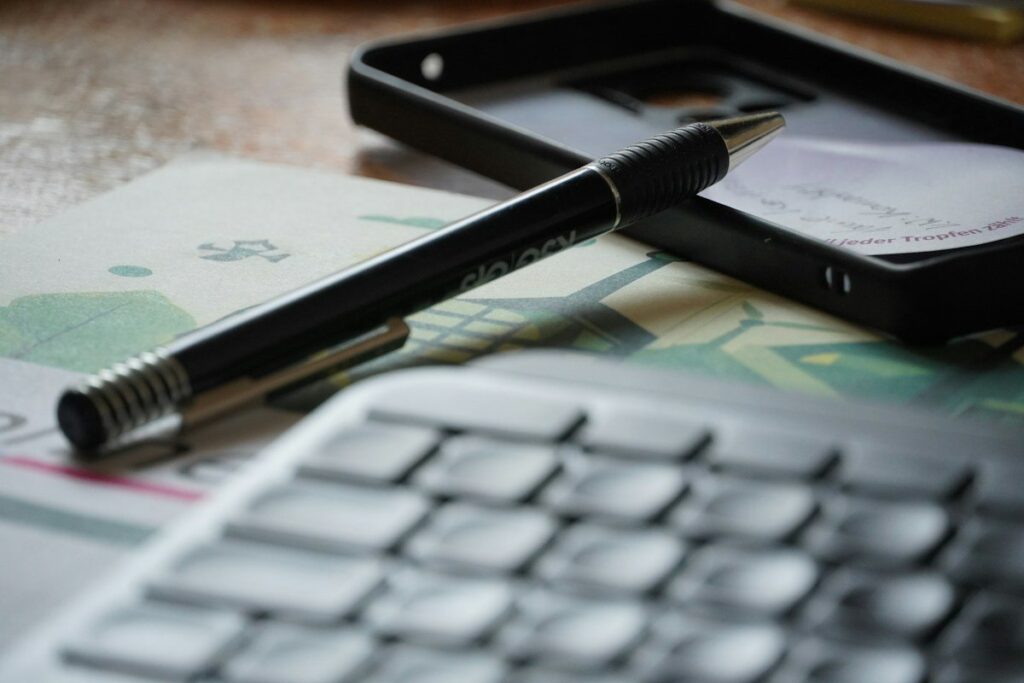 Pen and phone resting on a calculator keypad on a desk