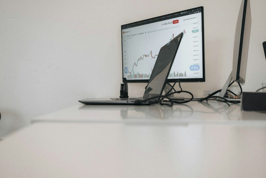 Laptop and monitor on an office desk, both showing price charts