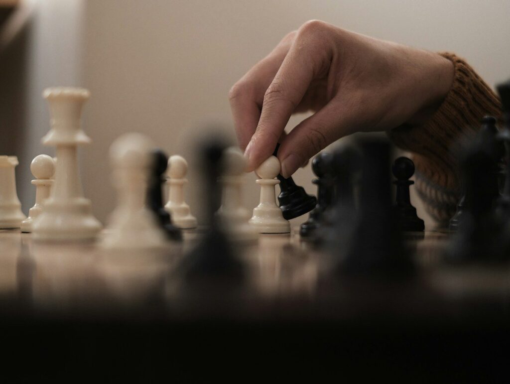 Chess player resting chin on hand studying the board, weighing up the downside before the next move