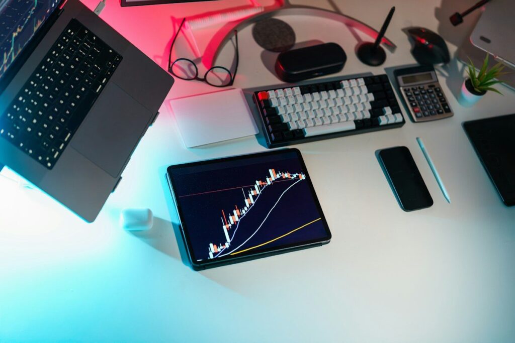 Desk with laptops and a tablet showing a currency chart