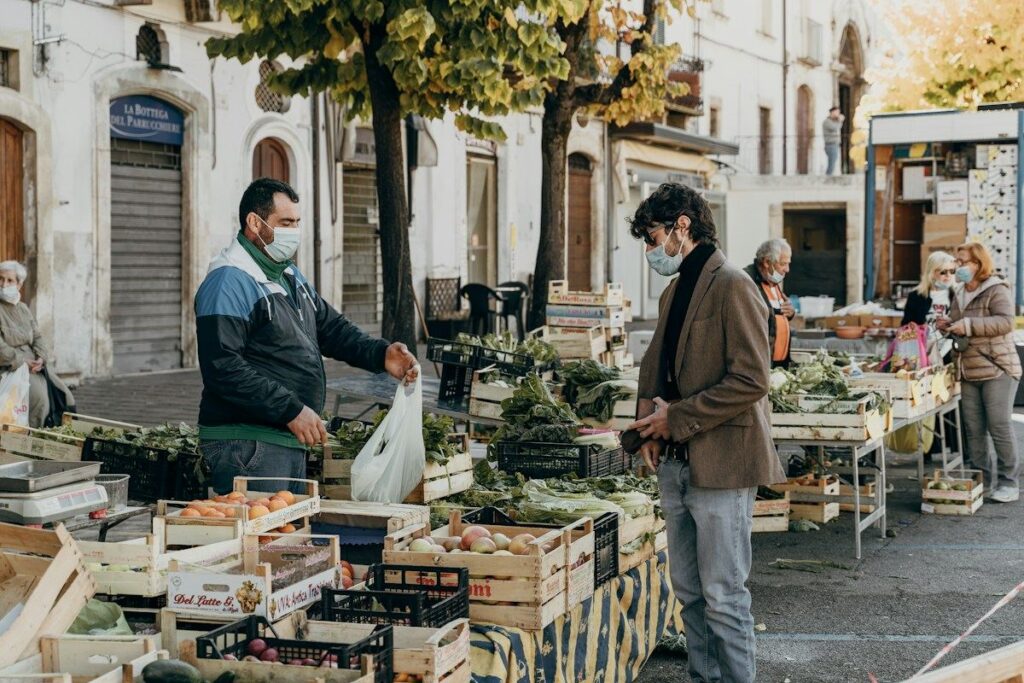 Greengrocer restocking crates at a stall, like a tested zone refreshed by a new sharp departure