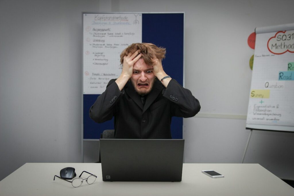 Frustrated trader with hands on head at a laptop after a loss, the moment revenge trading starts