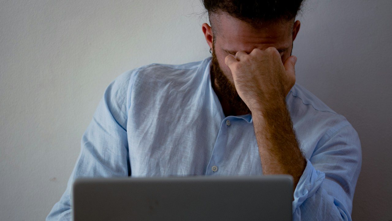 Trader with head in hands at a laptop after a losing streak, tempted by the gambler's fallacy in trading