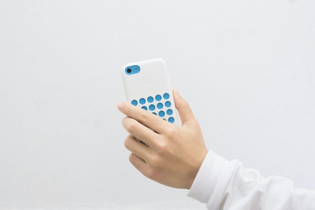 Hand holding a smartphone, ready to work out a forex stake per pip after US data