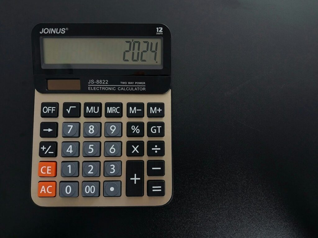 Hand using a desk calculator to work out how indicator lag changes trade risk and reward