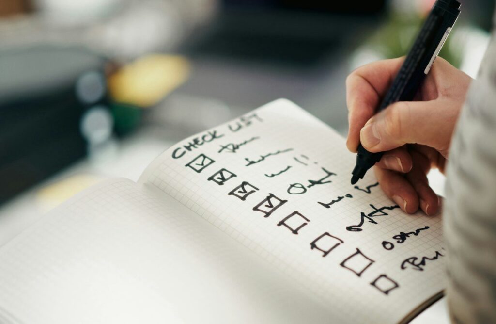 Hand ticking boxes on a paper checklist, writing trading system rules as yes or no checks
