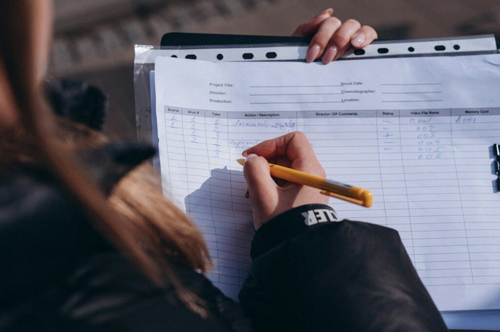 Person highlighting the busiest row on a printed spreadsheet, like finding the point of control