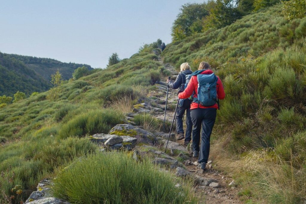 Two hikers climbing stone steps on a hillside, like an uptrend making higher lows for a trailing stop to follow