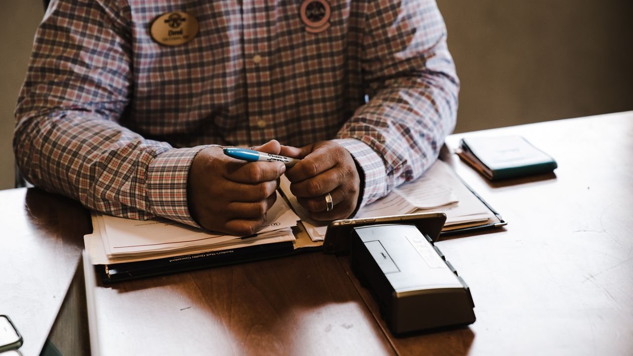 Person with a pen and folders at a desk while learning how to develop your own trading system
