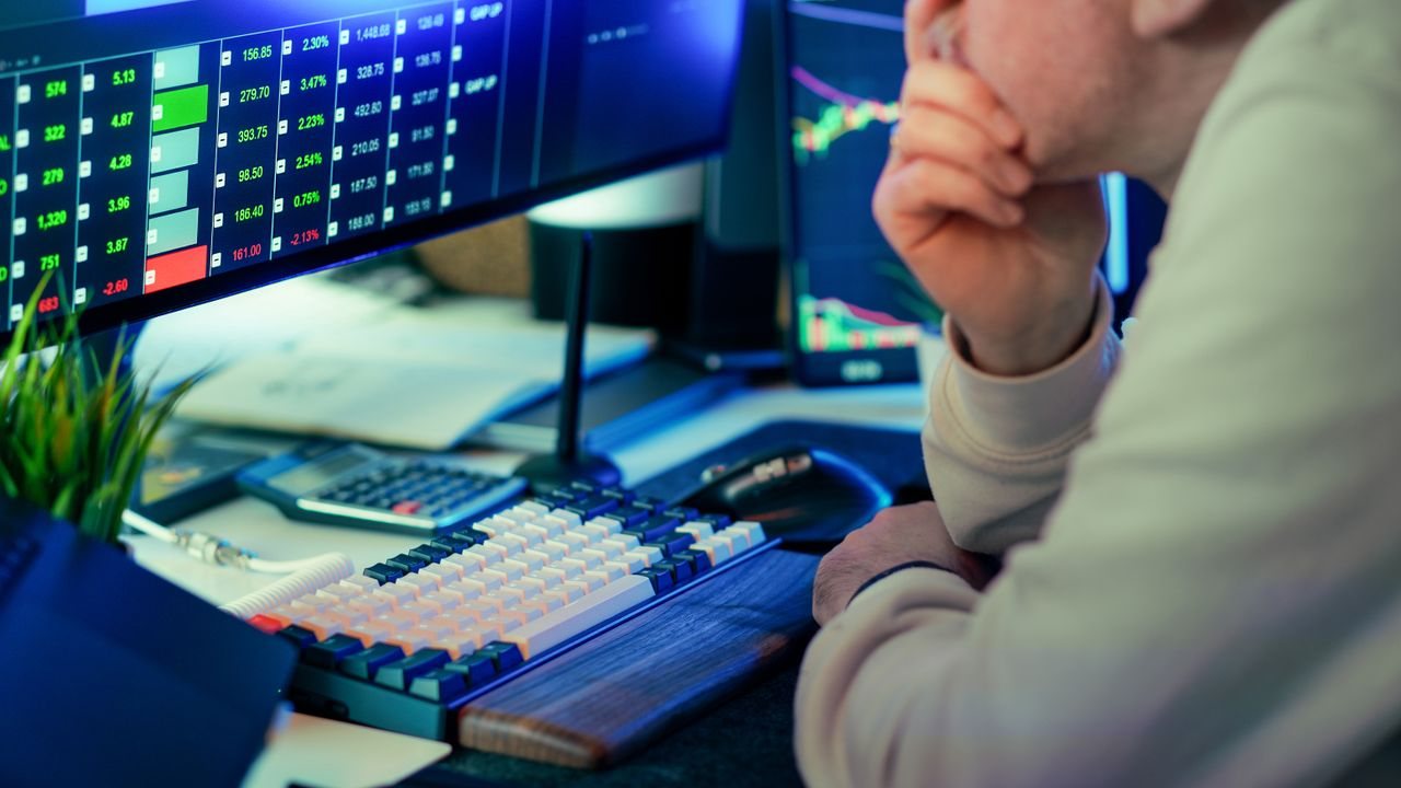 Man with his hand to his face at a desk of chart monitors