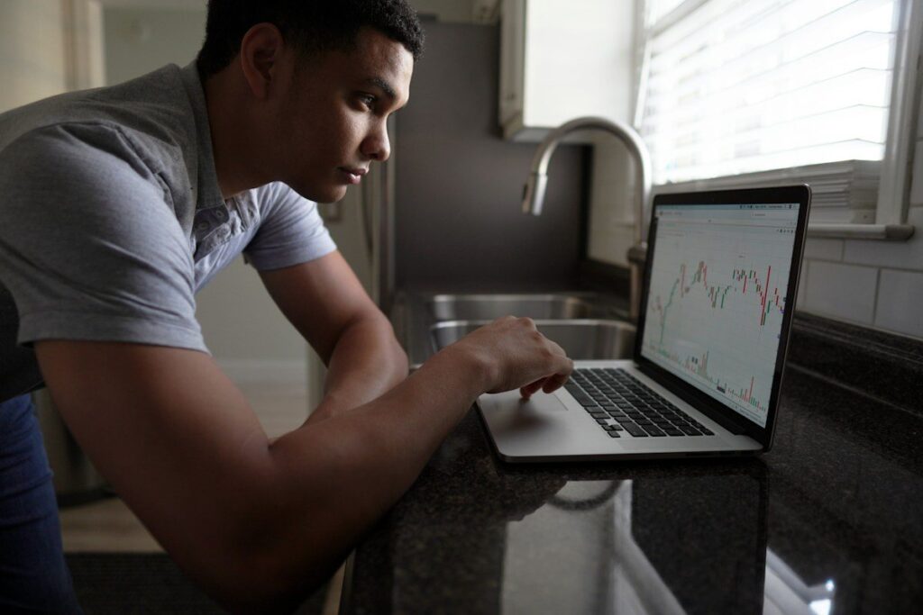Man leaning on a kitchen counter, looking at a laptop chart