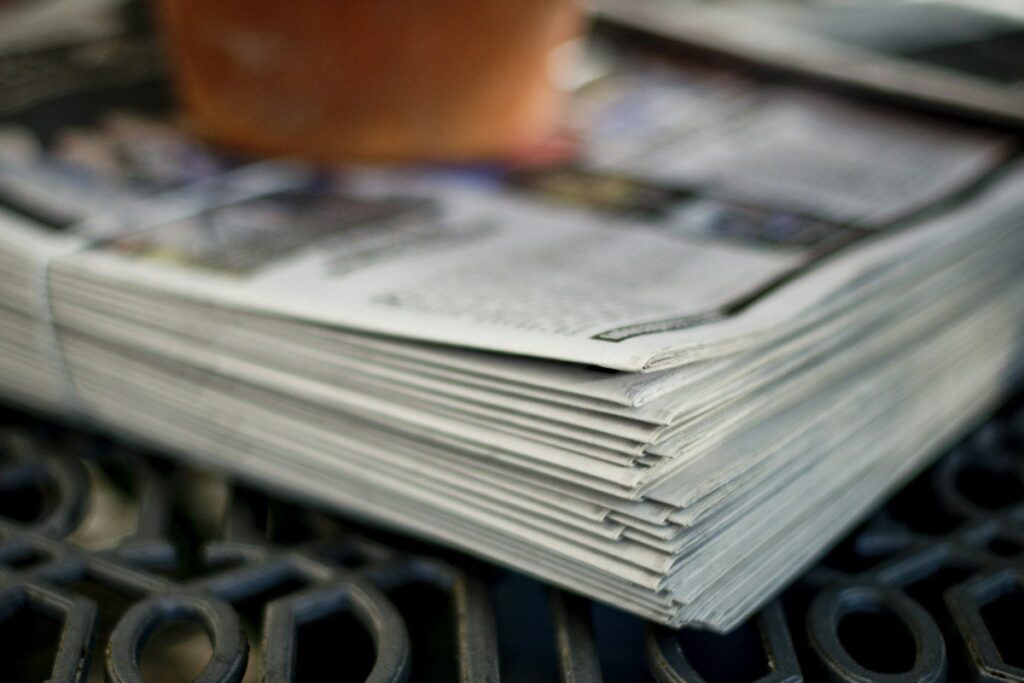 Folded newspaper business pages on a cafe table, showing the kind of news that moves stock indices