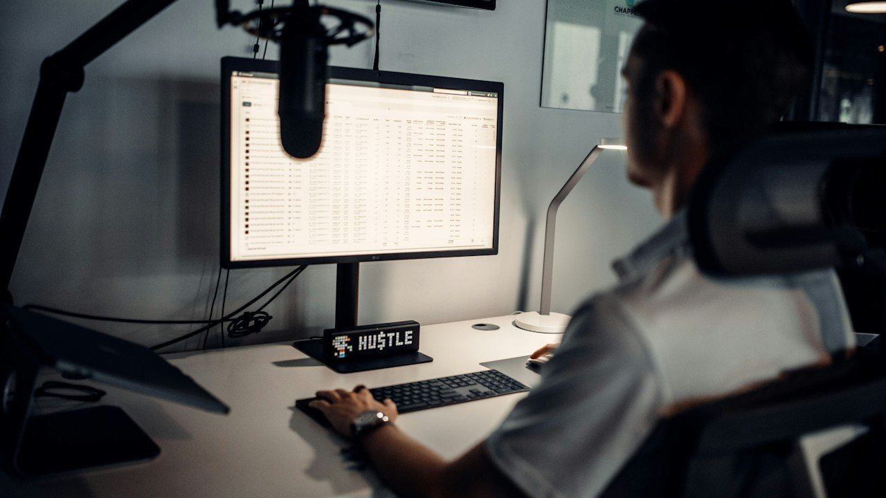 Man at a desk with a spreadsheet on his monitor