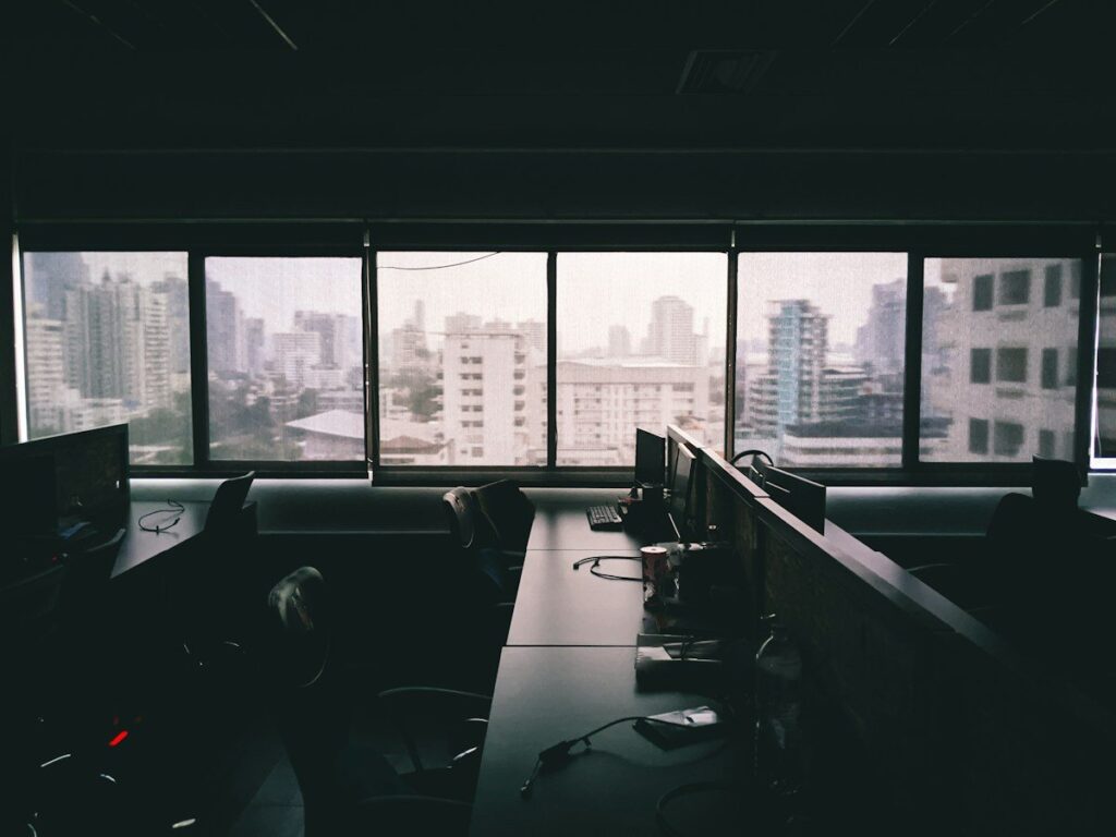 Empty office desks with monitors by a window