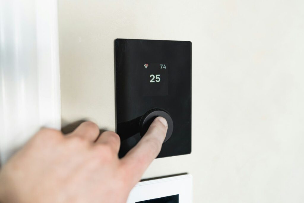 Hand turning down a wall thermostat, like cutting risk per trade during a losing streak