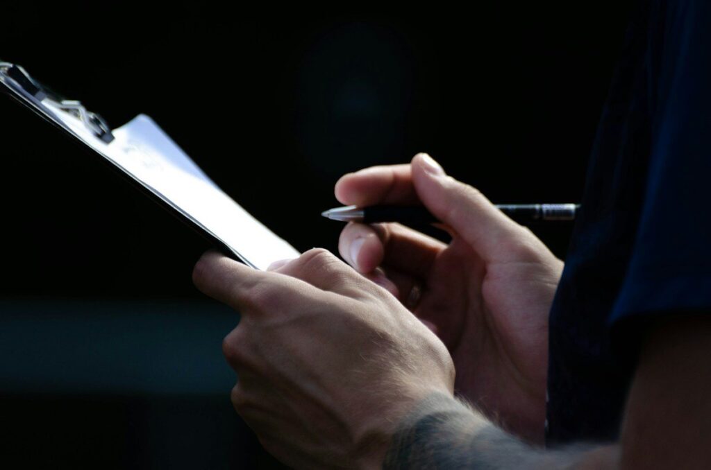 Person holding a pen over a clipboard, reviewing common mistakes before trading a flag or pennant