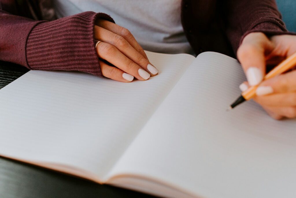 Person writing reflective notes in a journal after a session to understand trading psychology