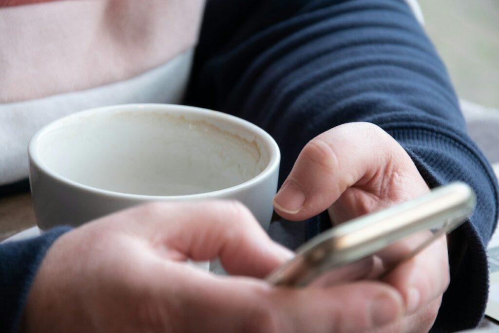 Hand holding a phone beside a coffee mug, waiting for an alert above a pin bar high