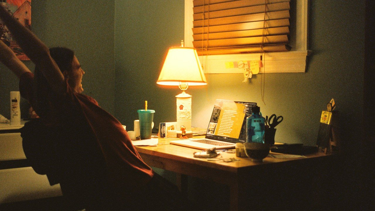 Person at a lamp-lit desk by a window in the evening, planning a pin bar trading strategy