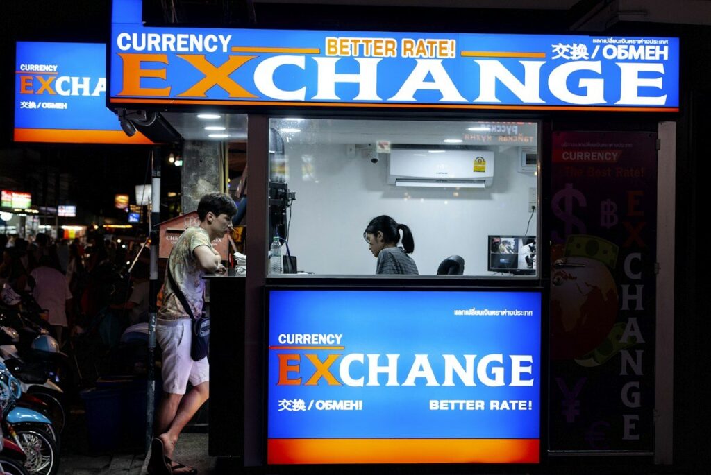 Currency exchange kiosk lit up at night, where every currency has a buy rate and a sell rate