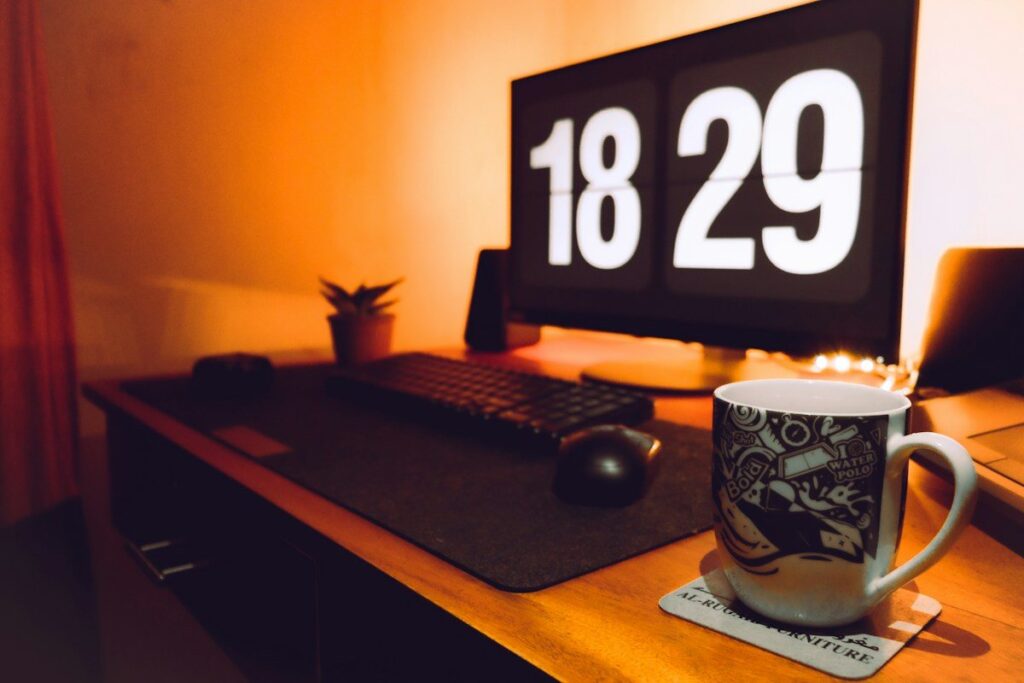 Desk with a large clock display and a mug in warm evening light
