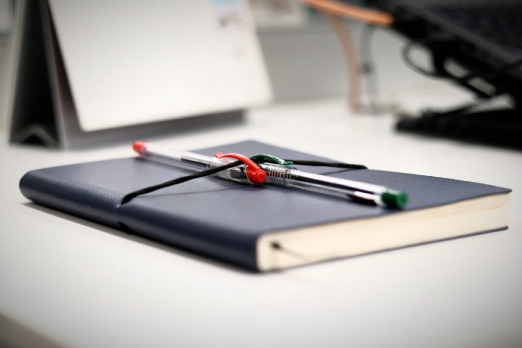 Closed notebook with pens on a desk, ready for a monthly review of which trades followed the rules