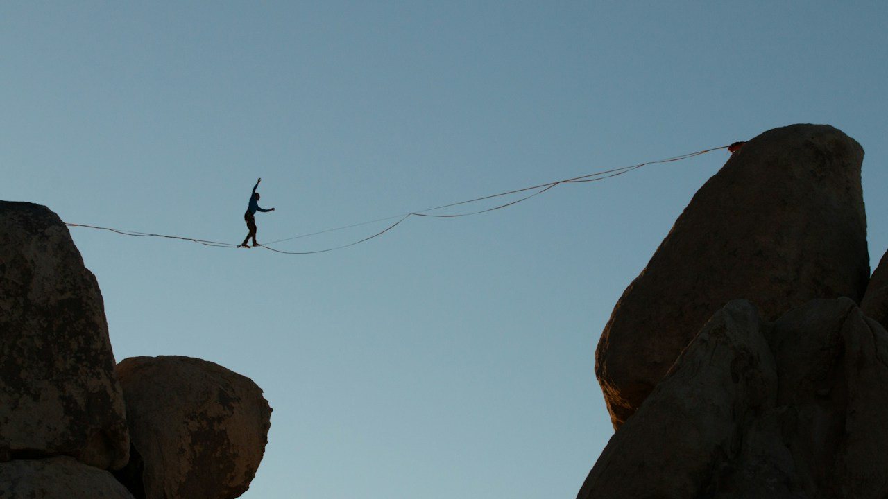 Tightrope walker balancing high above the ground, a picture of the risk of ruin every trader carries