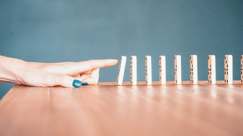 Wooden dominoes toppling in a row, like stop-loss orders adding to a move once a key level breaks