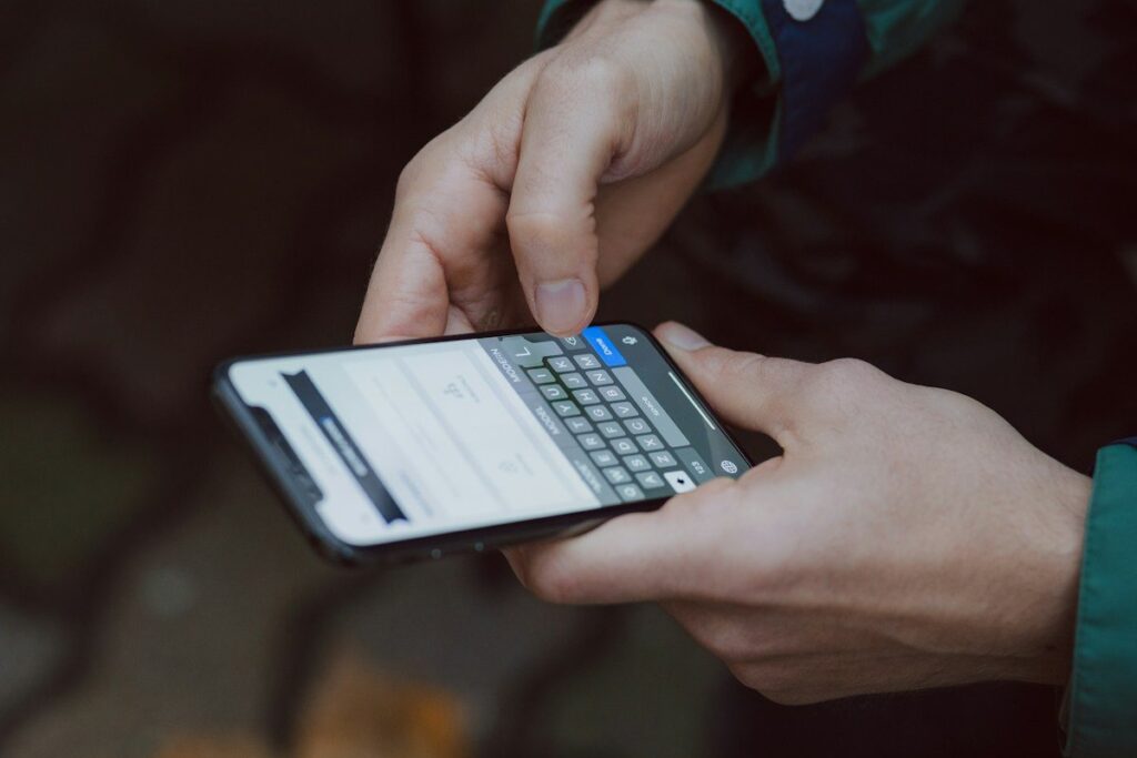 Hands typing on a smartphone to work out the position size for a gold trade after US data