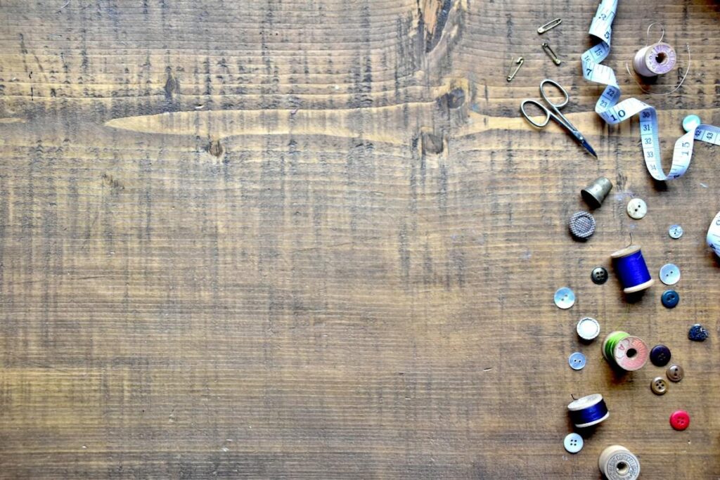 Tape measure and sewing items on a wooden table, like measuring the head to neckline height