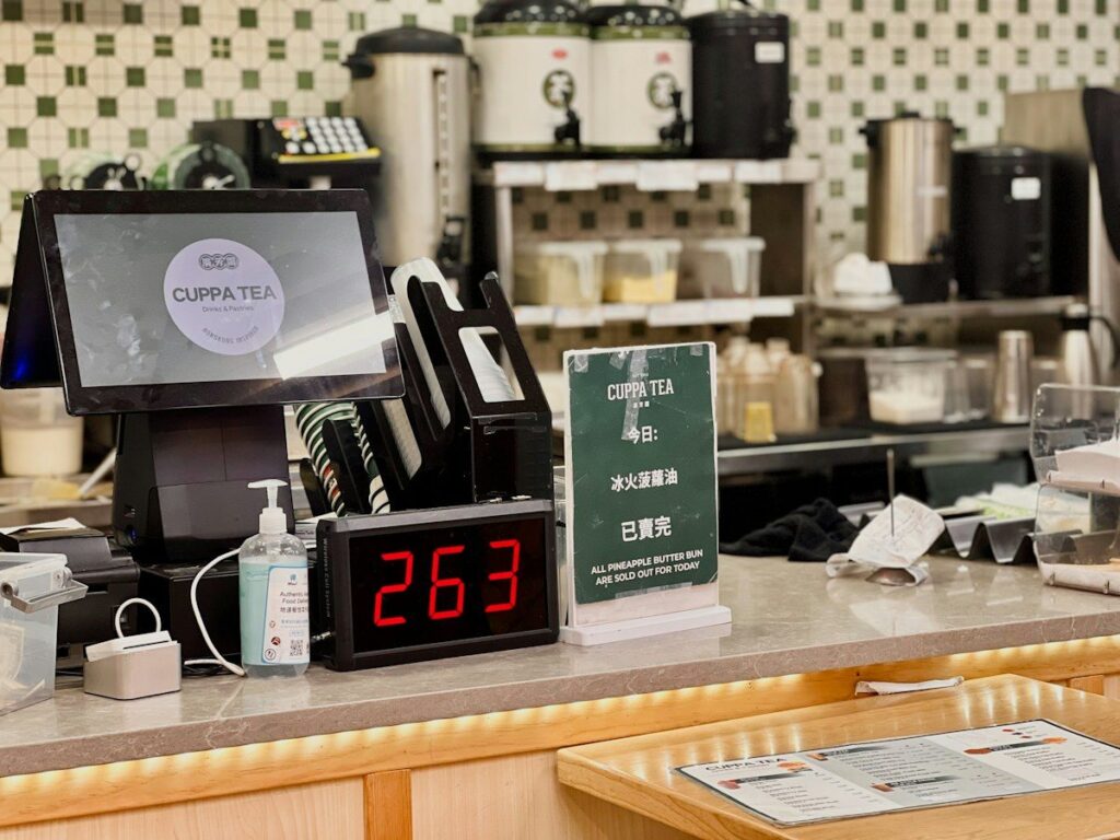 Shop counter with a till and order display, comparing the trading costs of spread bets and CFDs